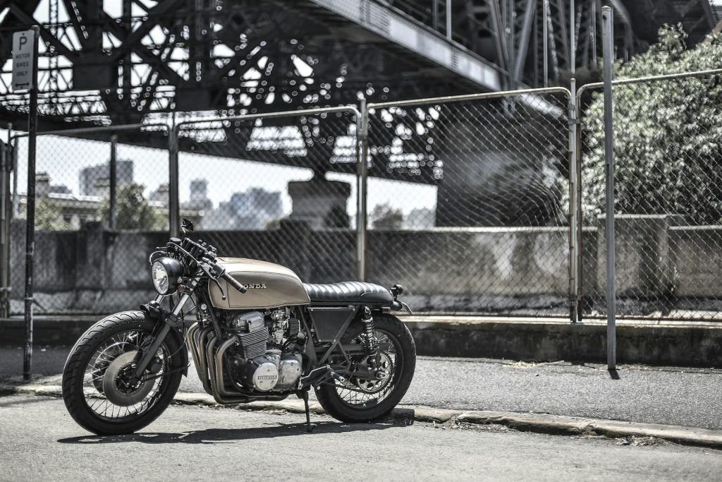 brown standard motorcycle near wire fence during daytime